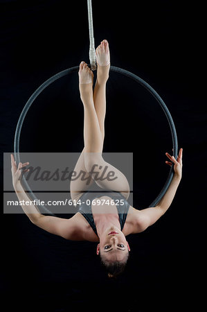 Aerialist performing on hoop in front of black background