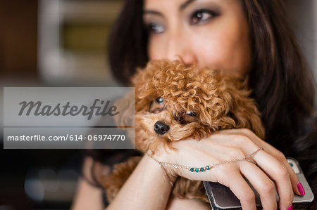 Portrait of mid adult female holding dog and smartphone