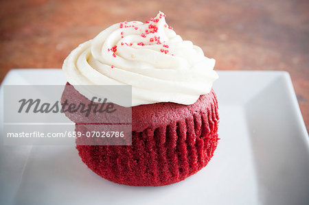 A Red Velvet Cupcake with White Frosting and Red Sugar Crystals