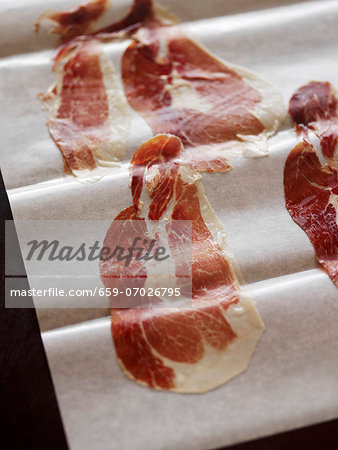 Thin Slices of Spanish Pata Negra Ham on Parchment Paper