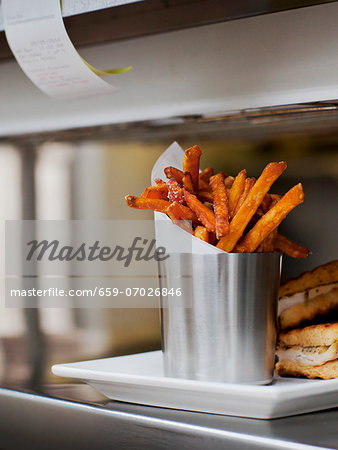 Seasoned Fries with Wax Paper in a Steel Cup on a Restaurant "Order-Up" Counter