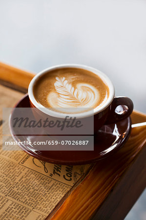 Latte with a Floral Design on a Newspaper Topped Table