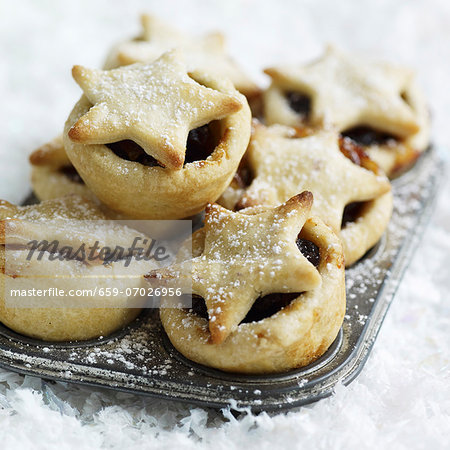 Mince pies dusted with icing sugar in the baking tin