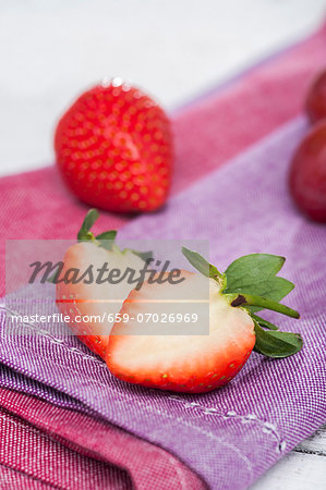 Whole and halved strawberries lying on a napkin