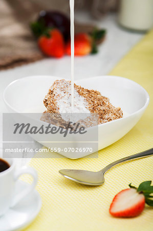 Milk being poured into a heart-shaped bowl of Weetabix