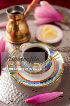 A Cup of Coffee with a Lemon Twist and a Pink Flower on a Silver Tray