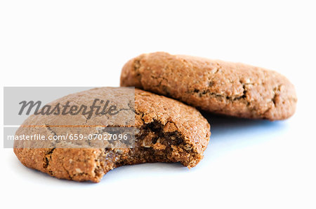 Two Oatmeal Cookies; One Bitten; On a White Background