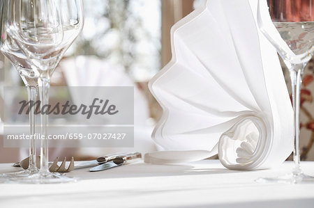 Artfully folded white napkins on a table laid for a meal Artfully folded white napkins on a table laid for a meal