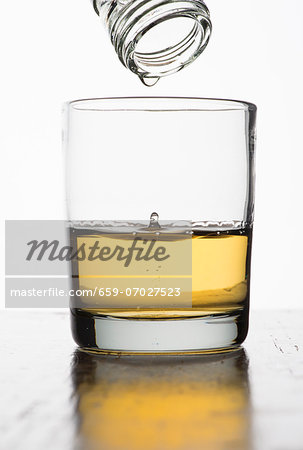 The last drop of whiskey dripping out of a bottle into a glass The last drop of whiskey dripping out of a bottle into a glass
