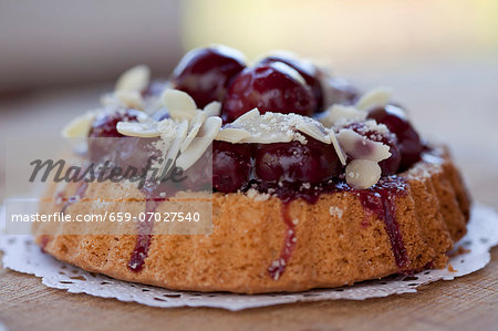 Individual cherry-topped cake with sliced almonds