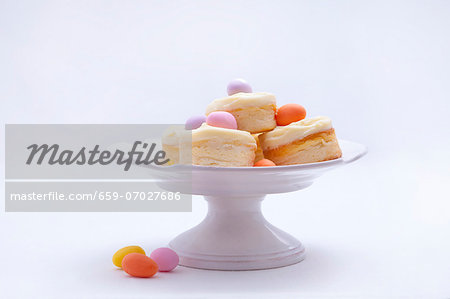 Mini cheesecakes with vanilla custard and marzipan eggs on a cake stand