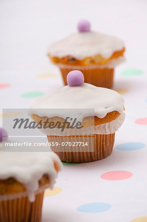 Three cupcakes topped with icing and marzipan eggs for Easter