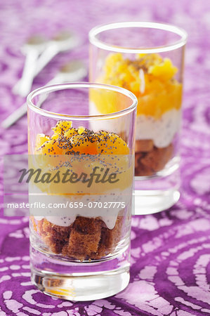 A layered dessert with oranges, gingerbread, whipped cream and poppy seeds