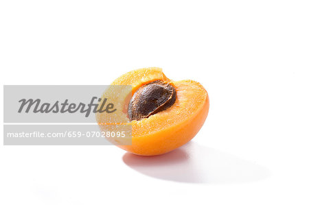 Half an apricot with the stone in against a white background