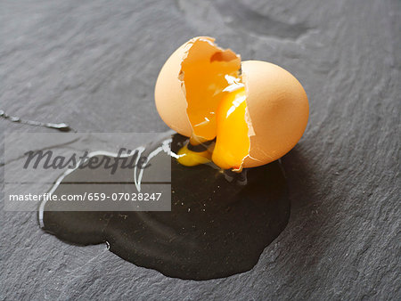 A cracked-open egg on a slate slab