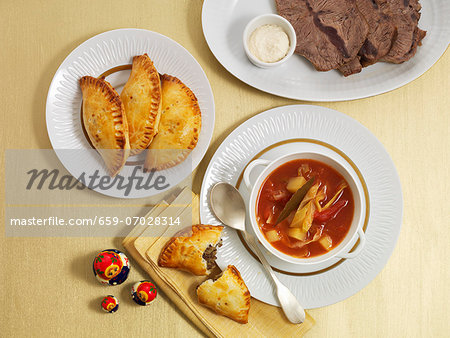 Borscht, served with meat pasties and a plate of sliced meat