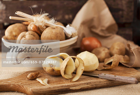 A still life featuring unpeeled and peeled potatoes