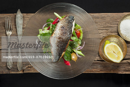 Nile perch on a bed of salad, with lemon and sea salt