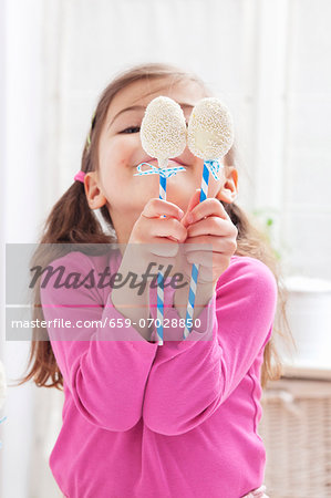 A girl holding two egg-shaped cake pops