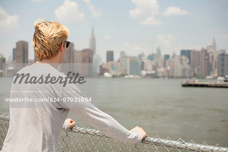 Young man looking at city skyline, Brooklyn, New York City, USA