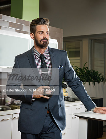 Young businessman holding cup in office kitchen