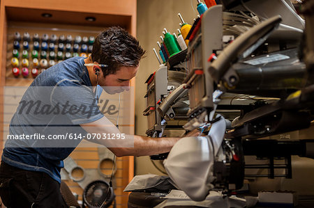 Worker preparing embroidery machine in t-shirt  printing workshop