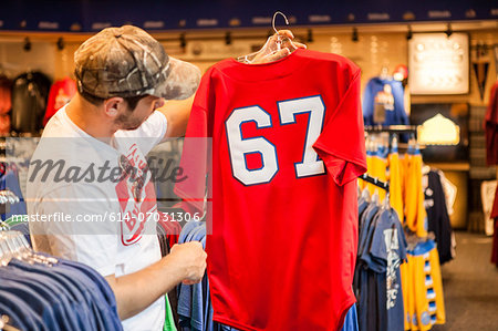 Man holding up t-shirt in store