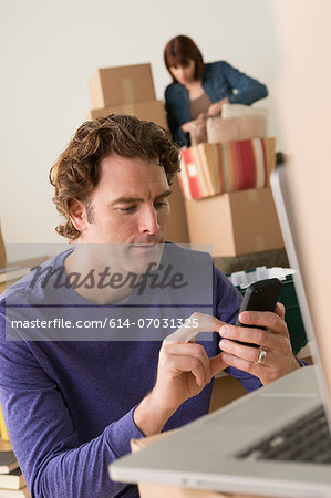 Man texting on cellphone whilst moving house