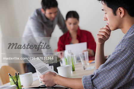 Male office worker reading papers at desk