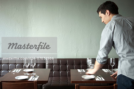 Waiter setting table in restaurant