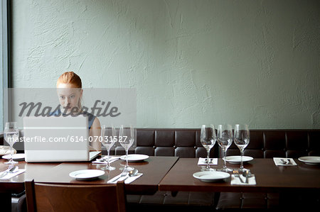 Young woman using laptop in restaurant