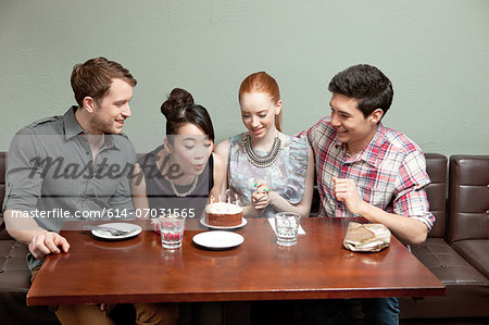 Four friends celebrating birthday in restaurant