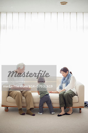 Boy with his mother and grandfather on sofa