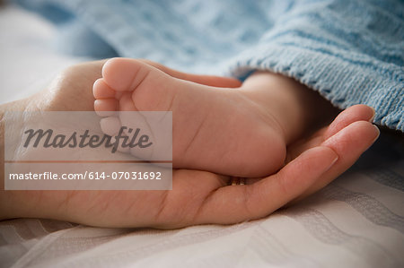 Mid adult woman holding baby boy's foot
