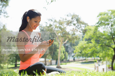 Young woman listening to mp3 player in park