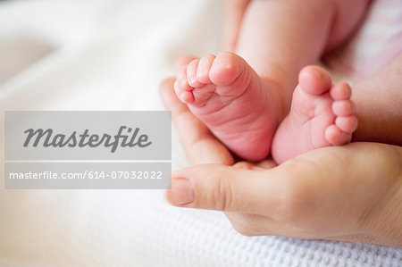 Mid adult woman holding baby girl's feet, close up