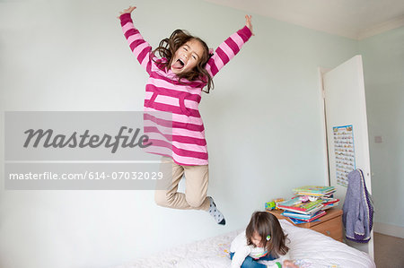 Girl jumping on bed and pulling face