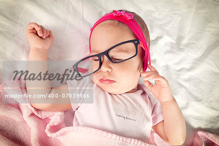 Funny sleepy baby with eyewear on her head