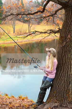 beautiful blond girl fishing in pond at autumn