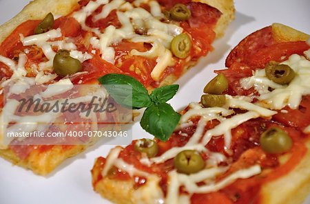 Baked pizza with tomatoes, cheese and olives on a white plate