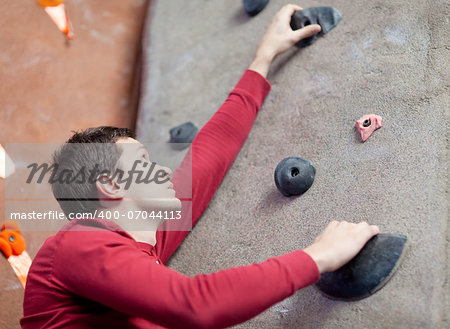 handsome young man rock climbing indoors