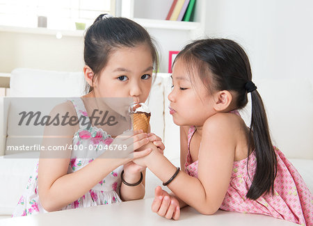 Eating ice cream cone. Asian children sharing an ice cream at home.  Beautiful girls model.