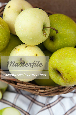 Fresh green and yellow apples in basket, close up