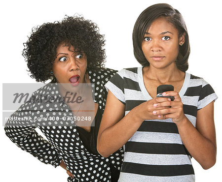 Shocked mother with teenage daughter texting on phone
