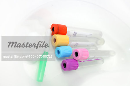 Unlabelled pathology phlebotomy, blood collecting vacutainer tubes a 21 gauge needle and cotton wool lying in a kidney dish for a blood collection procedure