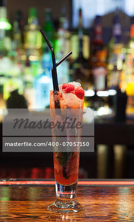 Close up on colourful cocktail with strawberries on the edge in a classy bar