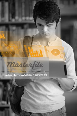 Focused handsome student working on his futuristic tablet in university library