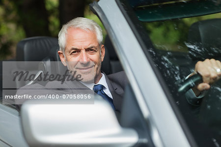 Content businessman driving expensive cabriolet on sunny day