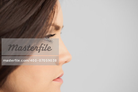 Brunette looking away on grey background