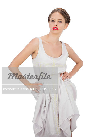 Severe model in white dress posing hands on the hips on white background